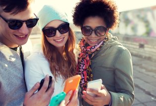 tre unge mennesker som ser på sine mobiler