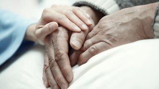 Hånd som holder hendene til et eldre menneske