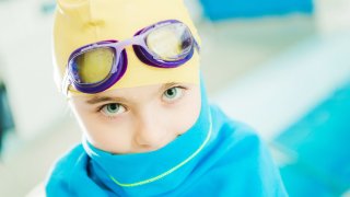 Nærbilde av jente med gul badehette og svømmebriller.
