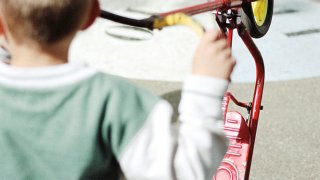 Gutt med rød sparkesykkel i skolegård