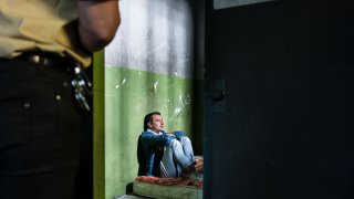 Fengselsbetjent ser inn i fengselcelle med en innsatt.